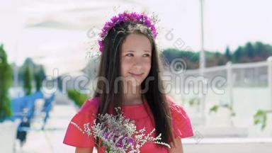 快乐的年轻女孩在手里嗅着花，在海湾酒吧微笑。 慢慢地