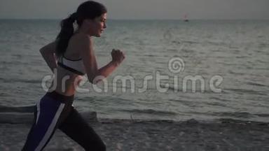日落时在海滩上奔跑的女运动员的肖像。 20岁的女孩在日落时在沙滩上奔跑。 慢跑