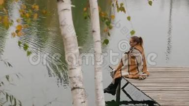 女人坐在柳树下的木凳上，在湖边迎风而动