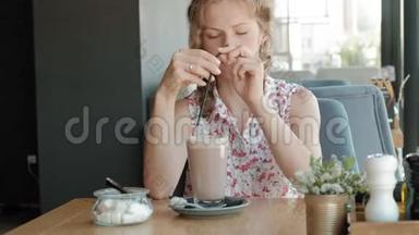 快乐的女孩喝咖啡，在咖啡馆里放松，微笑着看着智能手机