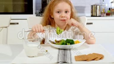 在家里的餐桌上，一个漂亮的小女孩高兴地吃着西兰花和青豆