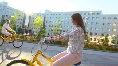 年轻<strong>快乐</strong>的女人在夏天的户外<strong>快乐</strong>地骑自行车穿<strong>过</strong>阳光明媚的街道。 年轻少女骑着自行车