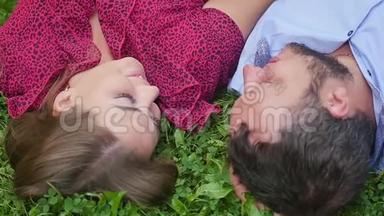 幸福的一对夫妇在<strong>绿草</strong>上的公园里休息。 慢动作。 微笑的男人和女人交谈，享受温暖的<strong>夏日</strong>