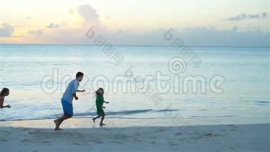 快乐的父亲和孩子们在海滩上玩。 暑假假期快乐的家庭