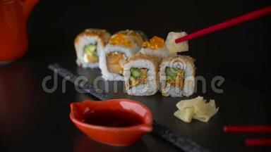 手拿红筷子从暗盘里拿卷寿司