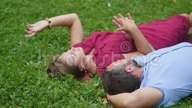 幸福的一对夫妇在<strong>绿草</strong>上的公园里休息。 动作缓慢。 微笑的男人和女人交谈，享受温暖的<strong>夏日</strong>