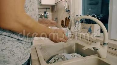 男人正在厨房里用肥皂洗盘子。 带有侧面<strong>摄像机运动</strong>的特写镜头