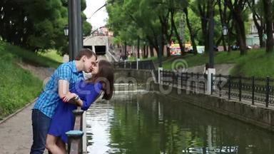 男人倚着女人，亲吻她在公园的小河边