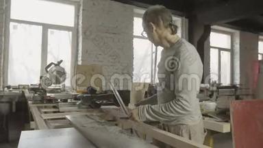 专业的成年木匠从工作台面上卸下抛光木板。