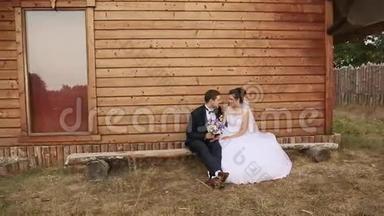 新郎新娘坐在老房子的长凳上