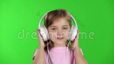 小女孩通过耳机听音乐。 绿色屏幕。 慢动作