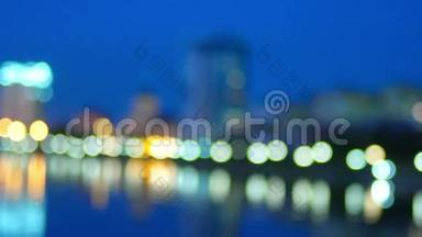 焦点之外的城市夜晚灯光反射在河流中。 Bokeh分散了城市景象