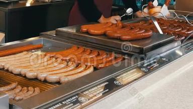 一位女售货员在烤架上烤香肠，布拉格市中心的街头食品，还有各种不同的香肠。