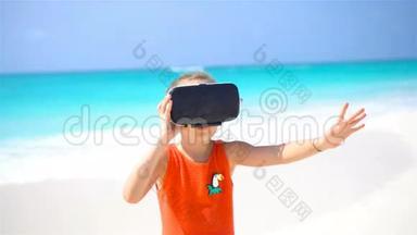 可爱的小女孩使用VR虚拟现实护目镜。 可爱的女孩看着白色海滩上的虚拟眼镜
