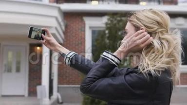 一个美丽的金发女孩的侧面肖像，她用智能手机<strong>上网</strong>，在一个郊区的家中拍摄自拍照片