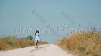 苗条的女孩经过沙质路去海滩
