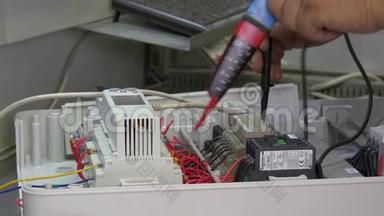 工人手检查工厂电子产品中的触点<strong>电压</strong>指示器。
