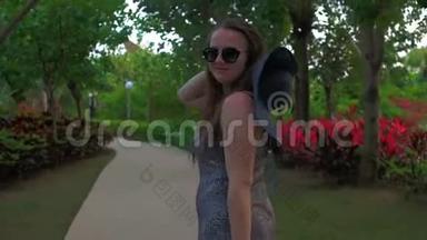 戴着蓝帽子的年轻女孩正穿过一个热带公园。 夏日时光。