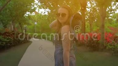 戴着蓝帽子的年轻女孩正穿过一个热带公园。 夏日时光。