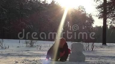 这个女孩冬天在树林里堆雪人。 太阳很亮。