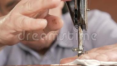 一个有胡子的成年男子在一台旧的手工缝制机器上缝制。