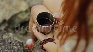 女孩拿着一杯热茶。 女孩在森林里喝茶。