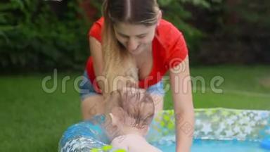 快乐微笑的小男孩在后院的充气游泳池里和妈妈玩耍