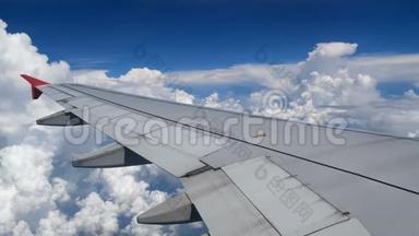 4K镜头飞机飞行。 在白云和蓝天上空飞行的飞机的翅膀。 窗外美丽的鸟瞰图