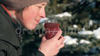 女人在森林里喝着热茶，美丽的冬天风景和雪杉树。