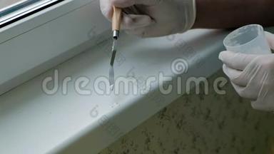 一个戴着橡胶手套的人用刮刀将窗台复原，用浆糊涂在破损的地方