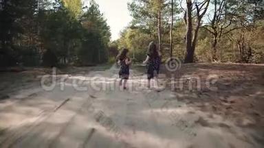 两个小女孩正在夏天的森林里奔跑