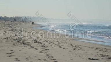 人们沿着圣莫尼卡码头附近的海滩散步。