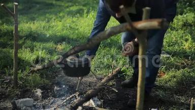 人在露营时把木头扔在火上。 清晨在森林里
