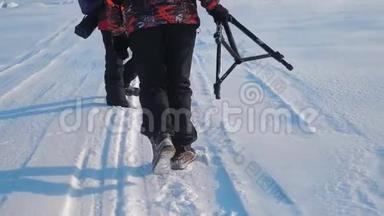 团队合作。 男游客摄影师冬天乘三脚架爬山顶山顶山顶群去下雪
