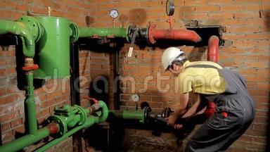 一名穿工作服的工人打开水阀.. 这个人包括锅炉房的暖气。