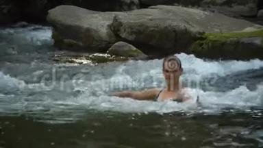 女人在<strong>河里</strong>洗澡。 一个年轻漂亮的女人沐浴在干净的山<strong>河里</strong>。 她很开心。