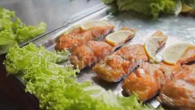 烤红鲑鱼加沙拉。 桌上放着青菜和柠檬的煮熟的鱼片。 美食节上烤鱼