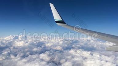飞行在云层之上的飞机的机翼。 人们从飞机的窗口看天空，用空中交通工具