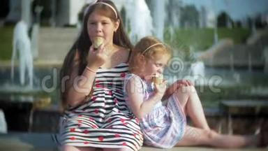 儿童，小女孩在炎热、炎热的夏日吃冰淇淋，孩子们在喷泉附近