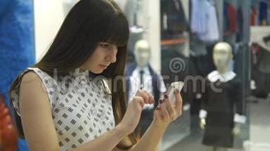 年轻女子在购物中心玩口袋妖怪，在室内玩，使用智能手机。 女孩玩流行的智能手机游戏-