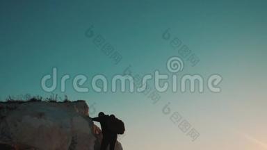 一位游客在日落探险时爬上山顶的剪影。 生活方式的剪影