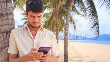 白色的家伙在沙滩棕榈树下经营iPhone