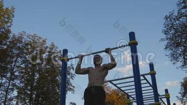 强壮的<strong>肌</strong>肉男在公园里做<strong>肌</strong>肉锻炼。 年轻运动员在户外<strong>水</strong>平杆上做下巴练习。 健身