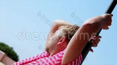 穿着<strong>粉色</strong>外套的人在海滩伞上对着镜头摆姿势。 风。 夏日阳光明媚。 <strong>蓝</strong>天