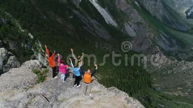攀登高峰。 快乐的人拥抱举起双手在尖岩石崖蓝天背景空中缓慢