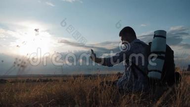 一个带背包的年轻游客使用手机。 在夕阳的光芒中.. 旅行概念。 <strong>一直</strong>在线。