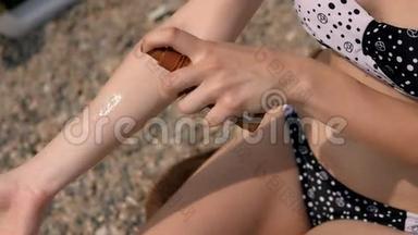 年轻女子在沙滩上用手涂抹防晒霜