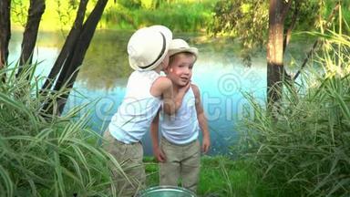 小兄弟钓完鱼后从湖岸上走.. 孩子们休息后愉快地散步. 兄弟会