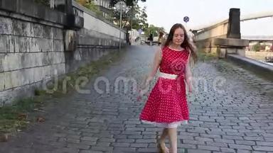 穿红衣服的年轻女孩沿着人行道城市海滨欢快地蹦蹦跳跳