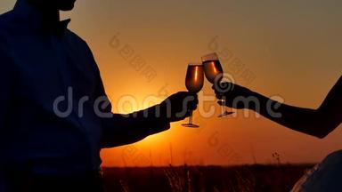 一对夫妇欣赏香槟酒的剪影。 阳光下的浪漫情侣自然剪影日落
